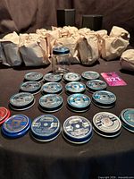 Group of wrapped jars, one unwrapped jar, and array of metal lids displayed