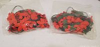 Two bags containing artificial red flowers on wiring
