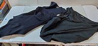 Two black bodysuits laid flat on table