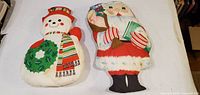 Snowman and Santa shaped pillows on white surface
