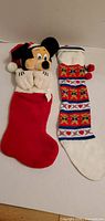 Front view of both Christmas stockings, Mickey Mouse plush stocking and patterned stocking
