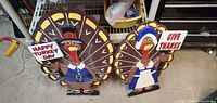 Front view of both wooden turkeys with signs visible