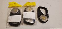 Front and back views of three TE-12 LCD keychain clips, two sealed, one loose