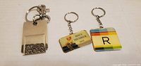 Front view of three keychains showing designs and text
