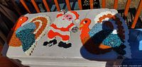 Overall view showing Santa decoration between two turkey decorations on a surface