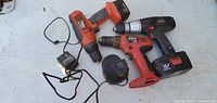 All three cordless drills, batteries and charger laid out