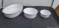 Top view of three white ribbed baking dishes in descending size order