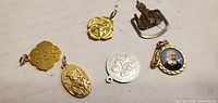 Six religious-themed charms laid out on table surface