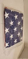 Folded American flag in plastic with blue field and white stars visible