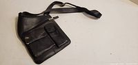 Full view of black leather shoulder bag with strap extended