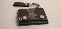Front of black wallet showing eagle graphic, snaps, chain, belt strap