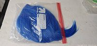 Blue synthetic wig in clear resealable bag front view