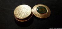 Closed case showing textured lid and green cabochon