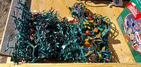 Two large piles of green-wire multicolour Christmas light strands in wooden crate