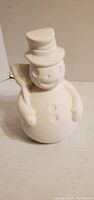 Front view of unpainted ceramic snowman with broom and buttons