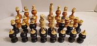 Full set of 32 large wooden chess pieces arranged in starting order, showing light and dark colours