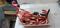 Bin containing red and white striped plastic candy cane pathway lights with wiring