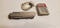 Front view of pocket knife, brooch, L&M lighter