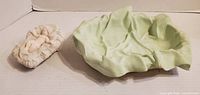 Baby Jesus figure on pillow beside green draped cloth base