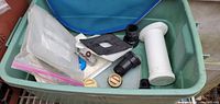 All items inside green tote, showing skimmer net, PVC fittings, brass caps