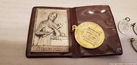 Fold-out brown vinyl pouch open showing St. Gerard plaque and gold-tone medal