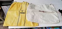 Yellow Fendi dust bag and white Salvatore Ferragamo dust bag side by side