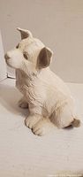 Front left view of seated unpainted ceramic puppy