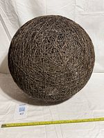 Overall view of woven hemp rope spherical lampshade with measuring tape for scale