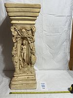 front view of plaster pedestal showing relief figure and chip at base