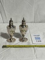 Front view of both silver plate shakers with ruler for scale