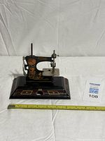 Full view of toy sewing machine with measuring tape for scale