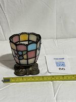 Full view of stained glass votive showing pattern and base with measuring tape for scale