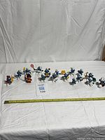 Full lineup of 17 Smurf figurines with measuring tape for scale