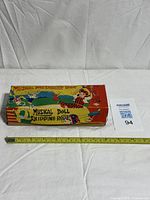 Full view of boxed toy with measuring tape indicating length ~12 in.