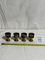 All four brass cups in a row with tape measure for scale