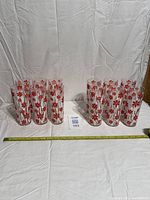 12 matching red floral tumblers in two groups with tape measure