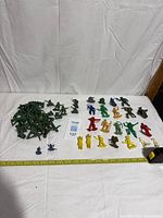 Wide view showing full lot with green army men pile, rows of multicolour warriors and measuring tape