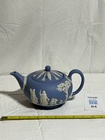 Full side view of teapot with lid on and measuring tape for scale