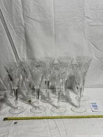 Eight Waterford Millennium flutes standing together with measuring tape for scale