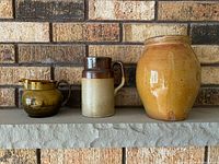 Front view of three pottery vessels on shelf