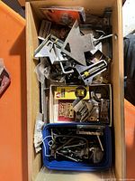 Drawer view of assorted framing clamps, packaged picture hanging hardware, loose fasteners