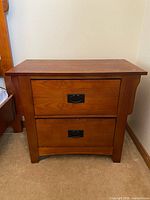 Front view of wooden bedside table with two drawers and metal handles