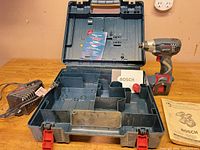 Open Bosch case showing impact driver, battery installed, charger, manual and insert