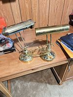 Pair of brass cylinder-shade desk lamps on wooden desk