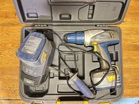 Drill, charger, side handle and empty battery bays inside case