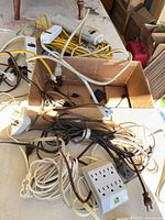 Pile of cords, power strips, wall tap and adapters on table