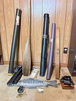 All items upright against wall showing paddle, tubes, board, sign, reel, spool, binoculars
