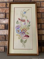 Front view showing floral needlepoint, matting and frame