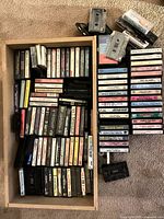 Overview of two boxes of assorted cassettes and loose tapes on carpet