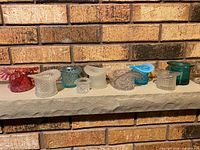 Front view of all ten Fenton glass top hats on shelf showing colour and pattern variety